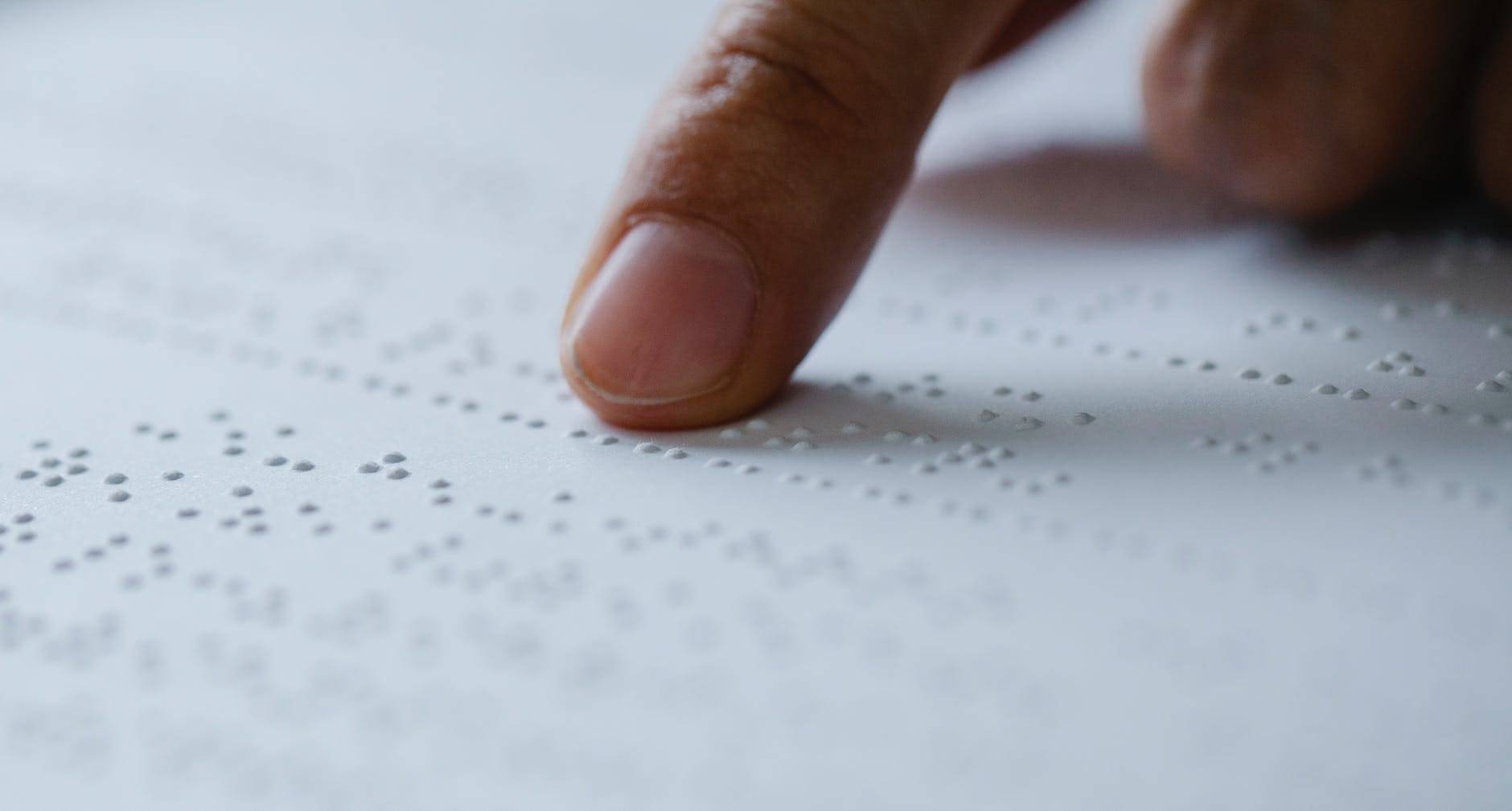 photo of person pointing on braille